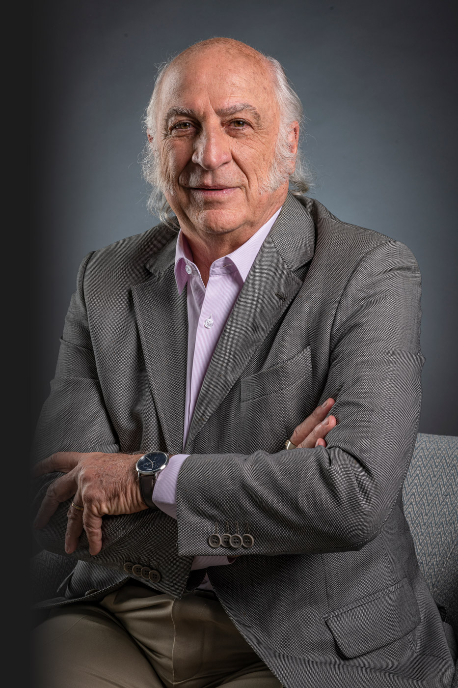 Sergio Palazzo olha para sua direção com um sorriso no rosto. Em posição de se levantar, ele se prepara para uma palestra.